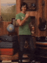 a man in a green shirt is standing in a room with a globe on the wall .