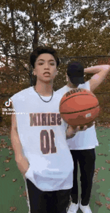 two young men are playing basketball on a court .
