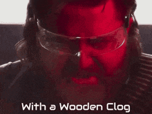 a close up of a man wearing safety glasses with the words " with a wooden clog " below him