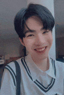 a young man wearing a white shirt and a black vest smiles