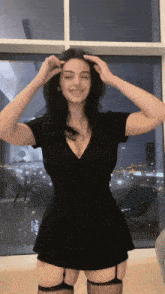 a woman in a black dress is standing in front of a window with a sign that says adv on it