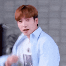 a young man in a blue shirt is making a funny face and looking at the camera .