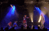 a group of people are on a stage with blue lights
