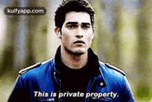 a man in a blue jacket is standing in a field and says `` this is private property . ''
