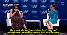 two women are sitting in chairs talking to each other and one of them is talking into a microphone .