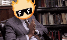 a man in a suit and tie is clapping his hands in front of a bookshelf with books on it