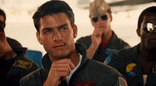 a group of men in military uniforms are sitting in a row and looking at the camera .