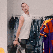 a man in a white tank top is standing in a closet