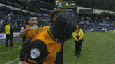 a man in a yellow jacket stands next to a man in an orange shirt