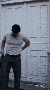 a man is standing in front of a white door with his hands in his pockets .