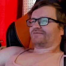 a man wearing glasses is sitting in a chair .