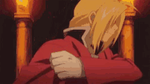 edward elric from full metal alchemist is sitting in a chair with his hands folded .