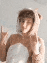 a young boy is wearing a teddy bear costume and making a rock sign .