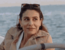 a woman wearing sunglasses and a trench coat is smiling