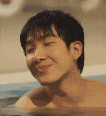 a shirtless young man is smiling in a bathtub