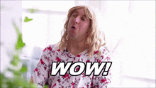 a man wearing a wig and a floral shirt with the word wow written on it