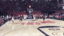 a basketball game is being played in a stadium with a large crowd watching .