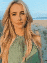 a woman in a green dress stands on the beach