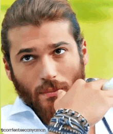 a man with a beard is wearing bracelets and a ring on his wrist .