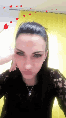 a woman wearing a black lace top and a necklace with a pendant that says ' i love you '