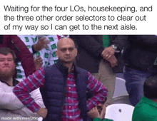 a man in a plaid shirt is sitting in a crowd with his hands on his hips .