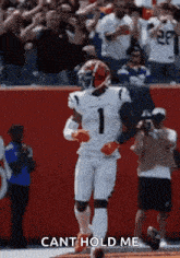 a football player is running on the field with a crowd behind him and a caption that says `` cant hold me '' .
