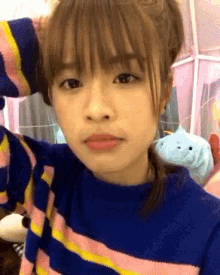 a girl wearing a blue and pink striped sweater takes a selfie