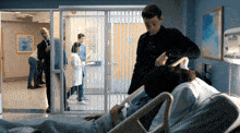 a man standing next to a hospital bed talking to a doctor