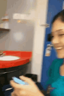 a woman is smiling while holding a cell phone in front of a bathroom sink