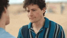 a man with curly hair wearing a blue striped shirt
