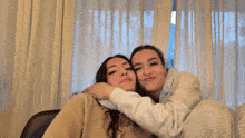 two young women are sitting next to each other in a room .