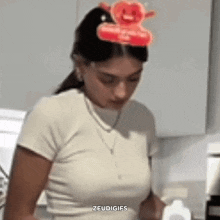 a woman in a white shirt is standing in a kitchen with a balloon in her hair .