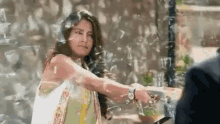 a woman is standing in front of a broken glass window holding a knife .