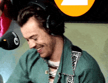 a man wearing headphones smiles in front of a microphone