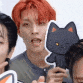 a man with red hair is holding a black cat shaped sticker .