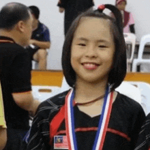 a young girl is wearing a medal around her neck and smiling at the camera .