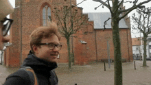 a man wearing glasses stands in front of a church