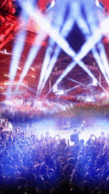 a crowd of people at a concert with blue lights coming out of the stage
