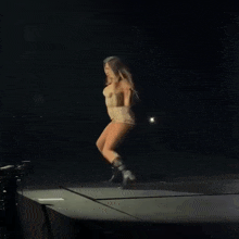 a woman is dancing on a stage with a camera in the background