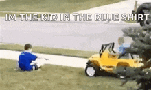 two young boys are sitting on the grass next to a yellow toy car .
