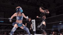 two women are wrestling in a ring and one of them is wearing a blue helmet