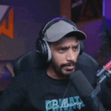 a man wearing headphones and a baseball cap is talking into a microphone .