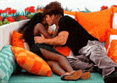 a man and a woman kissing on a couch with orange pillows