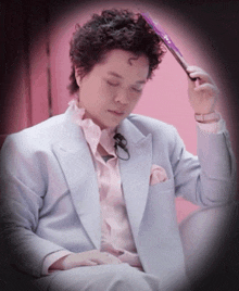 a man in a light blue suit is holding a purple fan