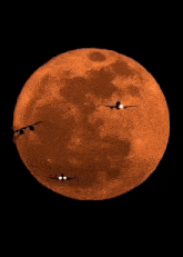 a plane is flying in front of a full orange moon
