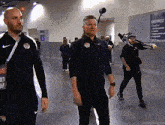 a man wearing a nike jacket is walking in a hallway with other men