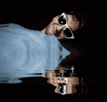 a man wearing sunglasses is laying down in the water