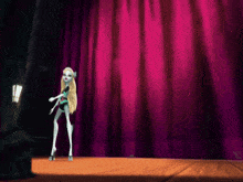 a monster high doll stands on a stage with a pink curtain behind her