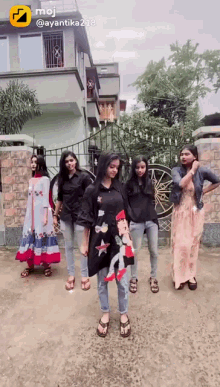 a group of girls are dancing in front of a building with a yellow emoji on the bottom