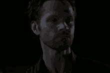 a close up of a man 's face in the dark with his eyes closed .